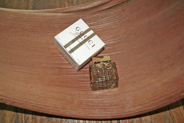 Ein Flakon und die Verpackung von „Gucci Première“ Eau de Toilette auf einer Holzoberfläche.