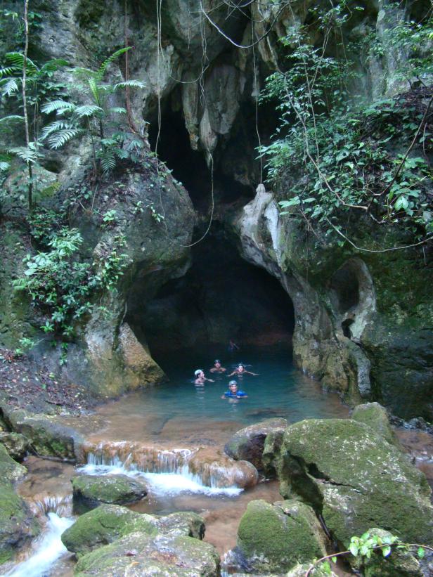 Eine Gruppe von Menschen schwimmt in einer Höhle mit türkisfarbenem Wasser.