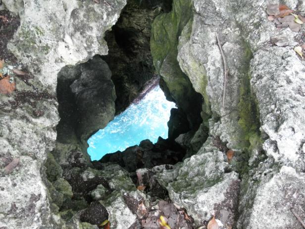 Ein Blick durch eine Felsöffnung auf das türkisfarbene Meer.