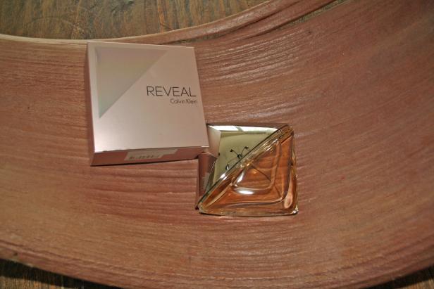 Ein Flakon des Parfüms „Reveal“ von Calvin Klein liegt neben der zugehörigen Verpackung.