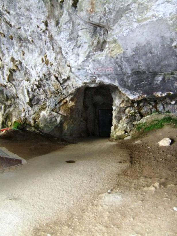 Ein dunkler Eingang führt in eine felsige Höhle.