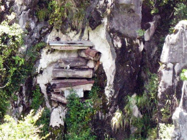 Hängende Särge in einer Felswand, dekoriert mit einem Schädel.