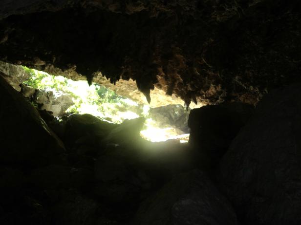 Blick aus einer dunklen Höhle auf das helle Tageslicht draußen.
