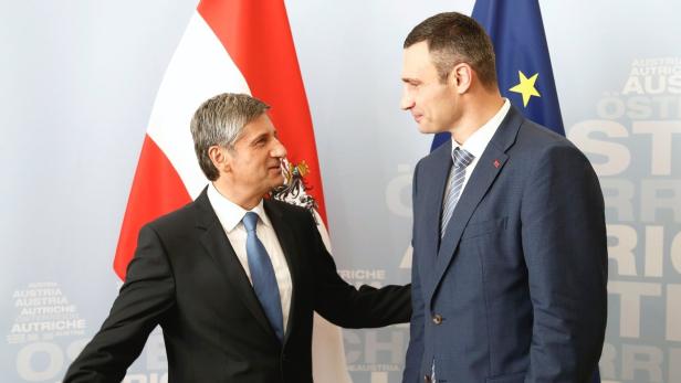 Bundeskanzler Karl Nehammer trifft Vitali Klitschko vor österreichischen und ukrainischen Flaggen.