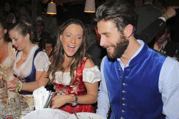 Lachende Menschen in Tracht sitzen an einem Tisch.