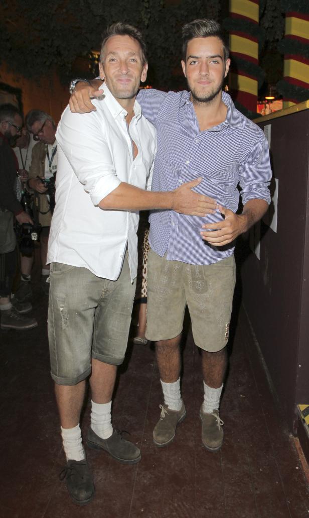 Zwei Männer in Trachtenlederhosen stehen nebeneinander und umarmen sich.