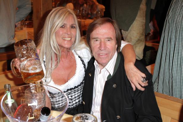 Eine Frau im Dirndl hält einen Bierkrug, während ein Mann daneben steht.