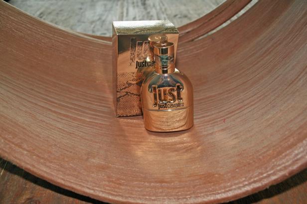 Eine goldene Flasche „Just Cavalli“ Parfüm steht vor der passenden Verpackung.