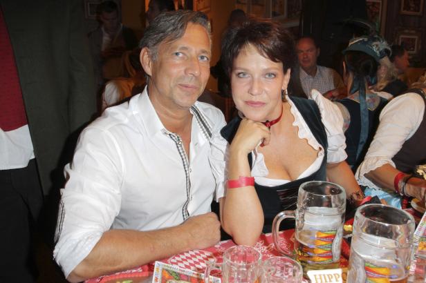 Ein Mann und eine Frau in Tracht sitzen an einem Tisch mit Bierkrügen.