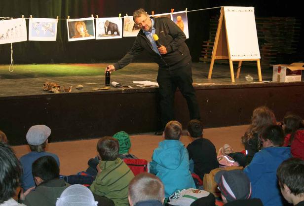 Ein Mann hält einen Vortrag vor Kindern über Evolution und Urgeschichte.