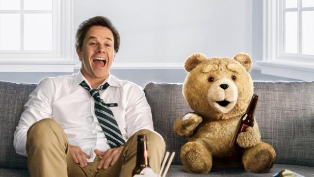 Mark Wahlberg sitzt mit dem sprechenden Teddybär Ted auf einer Couch.