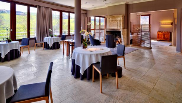 Ein elegant eingerichteter Speisesaal mit Tischen und Blick ins Grüne.