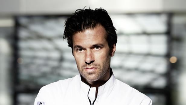 Porträt eines Mannes mit dunklen Haaren und einem weißen Hemd.