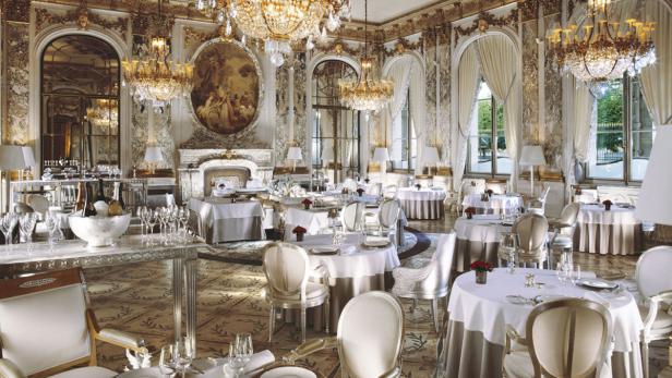 Ein prunkvoller Speisesaal mit Tischen, Stühlen und Kristalllüstern.