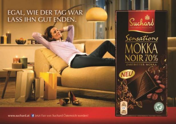 Eine Frau entspannt auf einem Sofa neben einer Tafel Suchard „Mokka Noir 70%“ Schokolade.