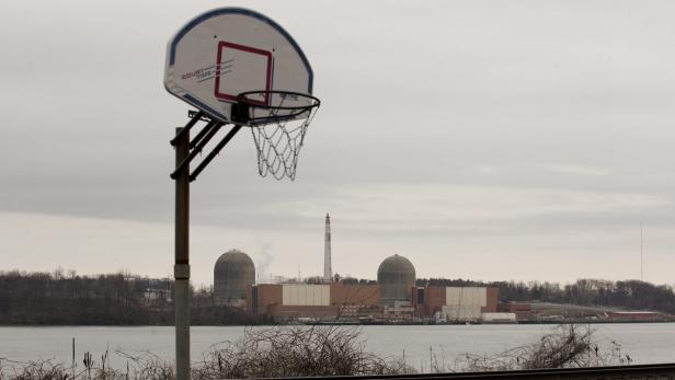 Ein Basketballkorb vor einem Kernkraftwerk unter einem bewölkten Himmel.