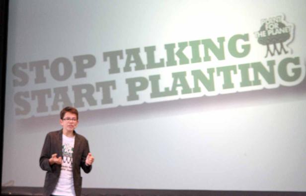 Ein junger Mann hält einen Vortrag vor dem Hintergrund „Stop Talking, Start Planting“.