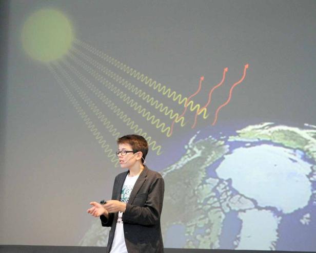 Ein junger Mann präsentiert eine Grafik zum Klimawandel mit der Arktis im Fokus.