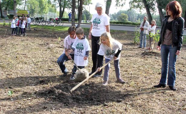 Eine Gruppe von Menschen, darunter Kinder, pflanzt Bäume für den Klimaschutz.