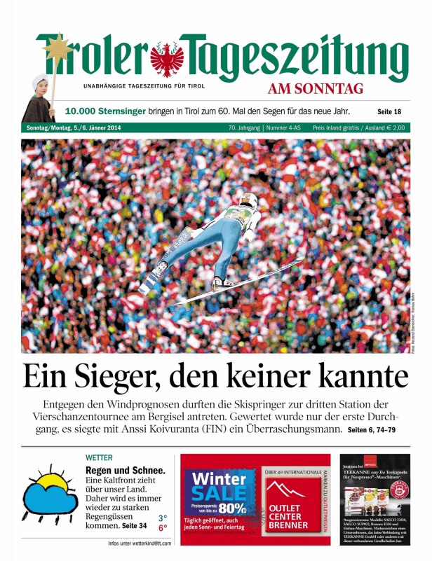 Ein Skispringer während eines Sprungs vor einer Zuschauermenge.
