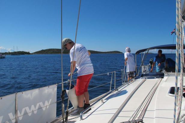 Eine Gruppe von Menschen segelt auf einer Yacht entlang der Küste.