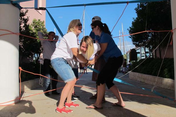 Drei Frauen spielen ein Spiel mit Seilen und Bändern im Freien.
