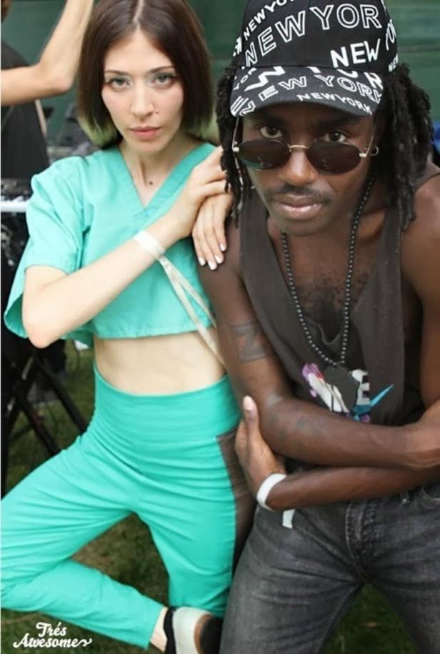 Eine Frau in türkisfarbener Kleidung posiert mit einem Mann mit „New York“-Kappe.