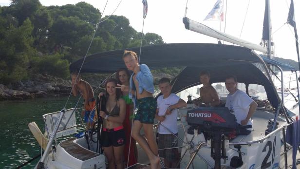 Eine Gruppe von Jugendlichen und ein Mann auf einem Segelboot.