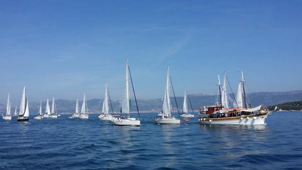 Mehrere Segelboote und ein hölzernes Ausflugsschiff auf dem Meer.