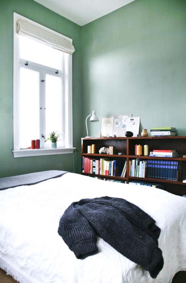 Ein Schlafzimmer mit einem Bett, einem Bücherregal und grünen Wänden.