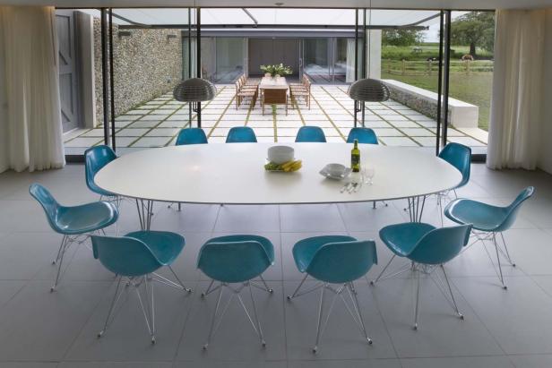 Ein Esstisch mit türkisfarbenen Stühlen in einem modernen Haus.