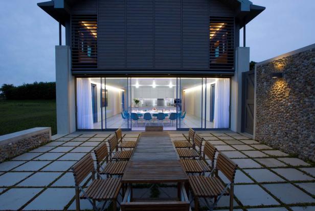 Blick auf ein modernes Haus mit Terrasse und Esstisch für ein Abendessen.