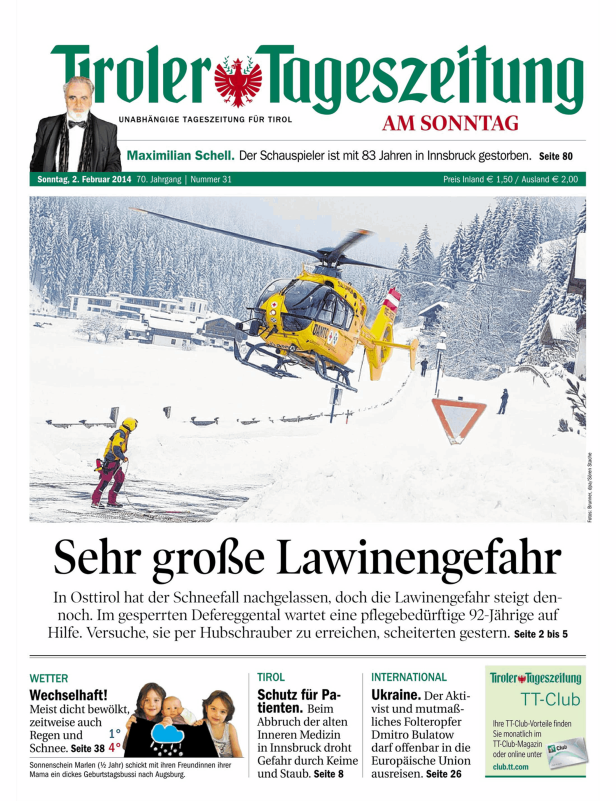 Ein gelber Rettungshubschrauber im Flug über eine verschneite Landschaft in Tirol.