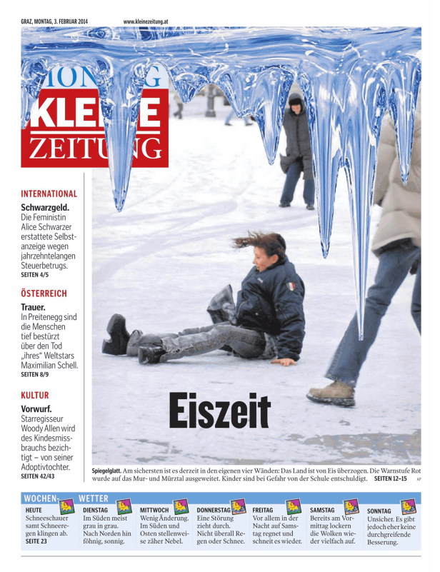 Menschen bewegen sich auf einer schneebedeckten Fläche unter überhängenden Eiszapfen hindurch.