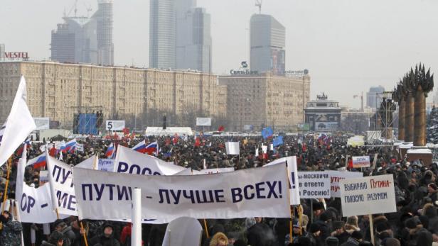 Eine Menschenmenge demonstriert mit russischen Flaggen und Bannern für Putin in Moskau.