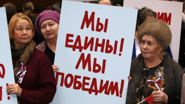 Frauen halten ein Schild mit der Aufschrift „Wir sind eins! Wir werden gewinnen!“.