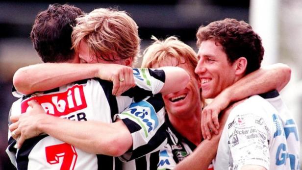 Mehrere Fußballspieler umarmen sich und feiern einen Sieg.