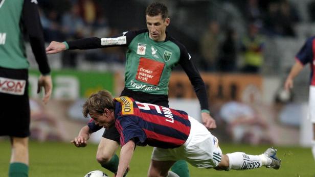 Zwei Fußballspieler kämpfen um den Ball auf dem Spielfeld.