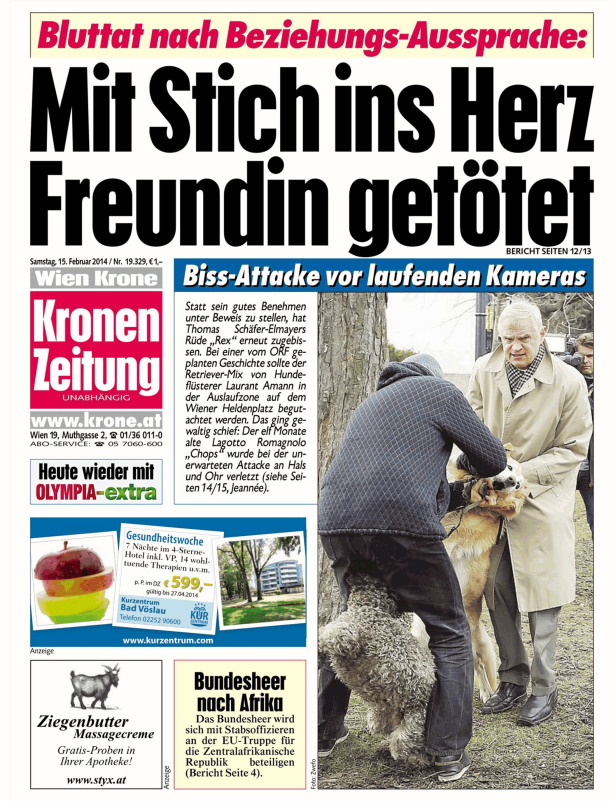 Ein Mann hält einen verletzten Hund fest, während ein anderer Mann daneben steht.