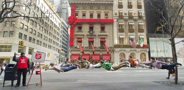 Mehrere Personen scheinen über eine Straße in New York zu schweben, während ein Mann für die Heilsarmee um Spenden bittet.