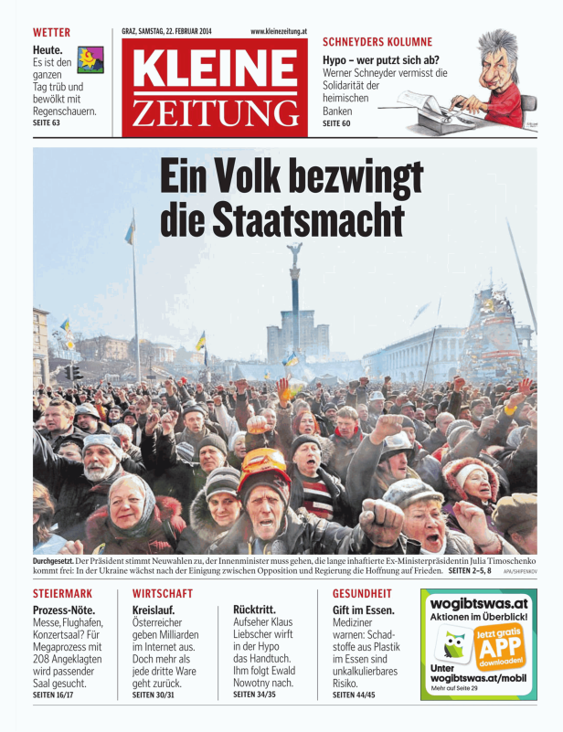 Eine Menschenmenge demonstriert mit ukrainischen Flaggen auf einem Platz.