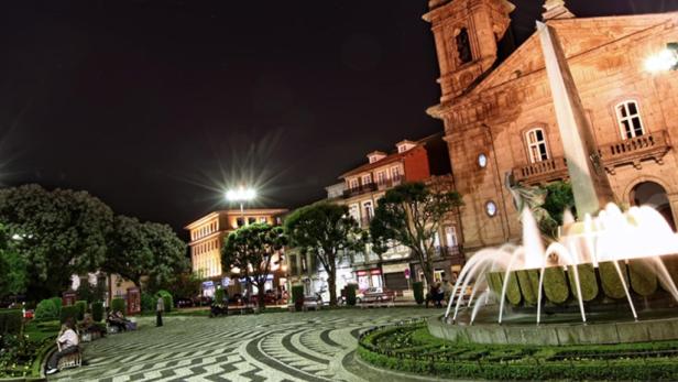 Nachts auf einem belebten Platz mit einem Brunnen und historischen Gebäuden in Braga, Portugal.