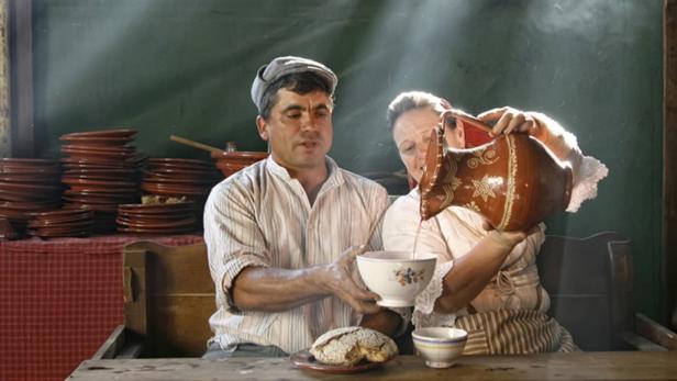 Eine Frau gießt ein Getränk aus einem Krug in eine Schüssel, die ein Mann hält.