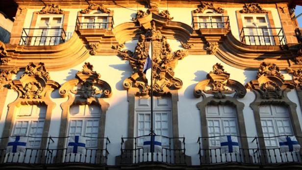 Die Fassade eines verzierten Gebäudes mit Flaggen an den Balkonen.