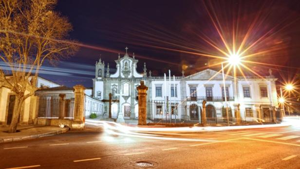 Nachts erstrahlt ein weißes Gebäude mit Kreuz und Turm in hellem Licht.