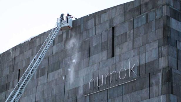 Feuerwehrleute reinigen die Fassade des Museums Numok mit einem Wasserstrahl.