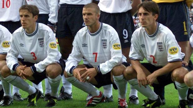 David Beckham und andere englische Nationalspieler hocken auf dem Rasen.