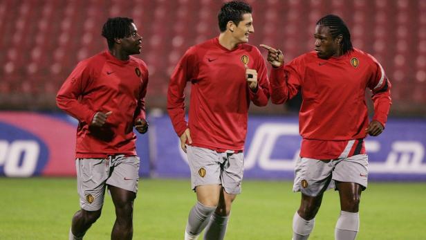 Drei belgische Fußballspieler in roter Trainingskleidung auf dem Spielfeld.