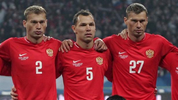 Drei russische Fußballspieler stehen nebeneinander in roten Trikots.
