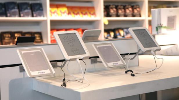 … Mehrere E-Reader der Marke Thalia stehen auf einem Tisch in einem Geschäft.